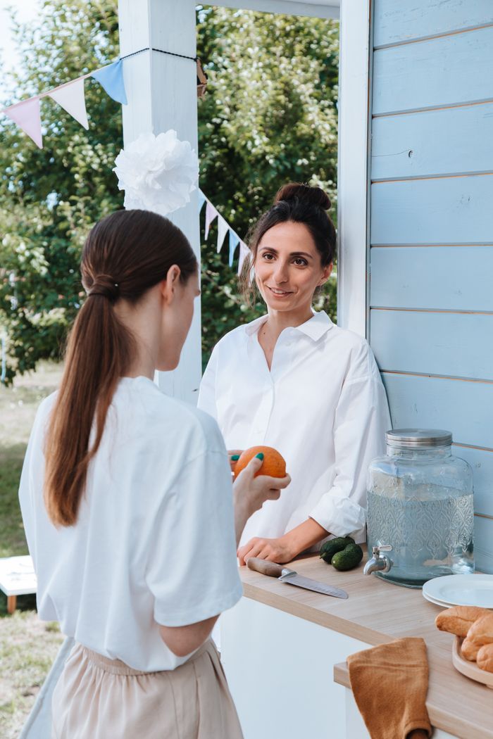 Two women enjoying a casual outdoor gathering with drinks and snacks.